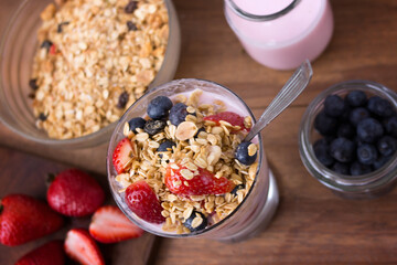 glass with yogurt, cereals, strawberries and blueberries on wooden table -  topview