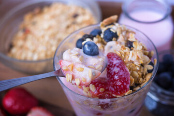 spoon serving yogurt, cereal, strawberries and blueberries - closeup