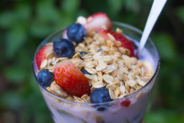 glass with yogurt, cereals, strawberries and blueberries - macro