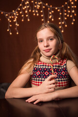 happy young girl with a Christmas candy in her hands against the background of lights
