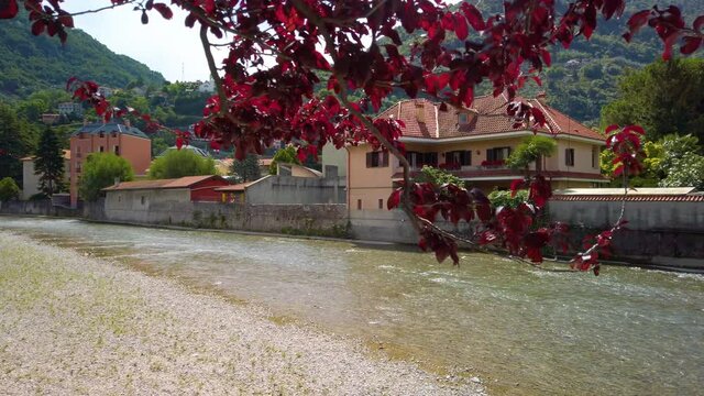 Stock video clip of river Pioverna in the city of Bellano, in Lake Como, Lombardy, Italy. Video taken upstream. There are houses and hills behind the river. It is a beautiful sunny summer day