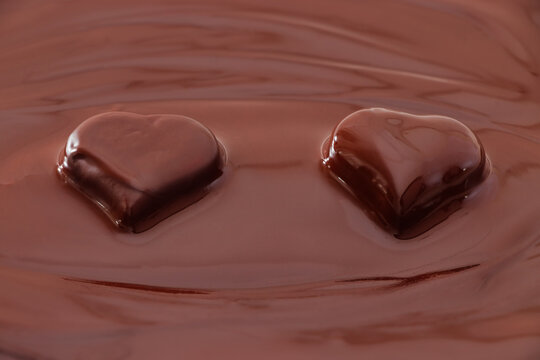 Two hearts covered with hot chocolate. The concept of a romantic meeting with a chocolate dessert. Chocolate background. 