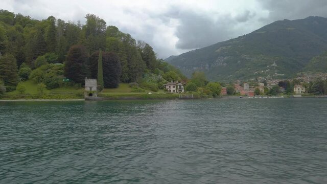 Short clip shot from a boat, sailing on Lake Como, close to the city of Lenno. It is an overcast, cloudy summer day. 4K slow motion
