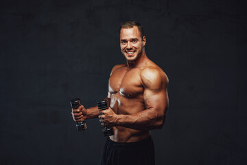 Fototapeta na wymiar Handsome brutal bodybuilder posing with dumbells