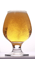 a glass of light beer with bubbles on a white background close-up