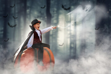 vampire boy on Halloween sits on a pumpkin in an artistic photo with a ghost that flies out of a flashlight