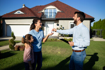 Real estate agent handing over keys of the new house to the single mother with her child.
