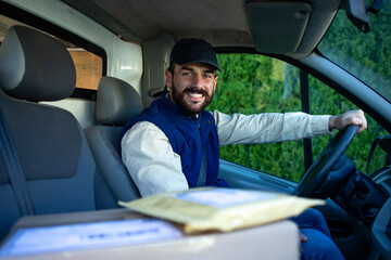 Portrait of professional deliveryman driving his van with packages. - obrazy, fototapety, plakaty