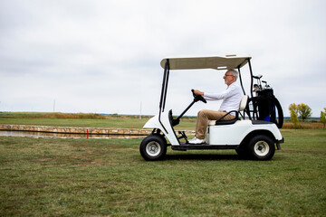 Shot of wealthy senior man driving golf car to the green zone to continue golfing.