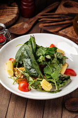 Healthy spinach salad with eggplant and baby corn on wooden background
