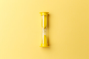 Modern yellow Hourglass with yellow background. Sand trickling through the bulbs of a crystal sand...
