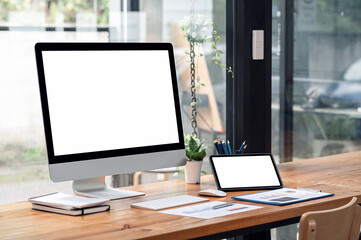 Mockup blank white screen destop pc and portable tablet on wooden table.