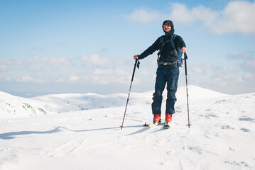 Backcountry skiing in the mountains. A happy young man who reached a summit and is ready to go...