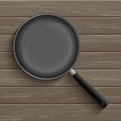 Frying black pan prepared for cooking your favourite meal is placed on a wooden table background.