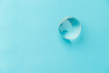 Glass globe on a light blue background. Nature concept for environment and conservation. Top view. Copy space. Flat lay