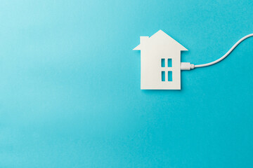 Fototapeta na wymiar The concept of a modern autonomous smart home. The power bank is connected to the house on blue background. Top view. Flat lay. Close-up. Copy space. Energy saving, environmental concept. Green energy