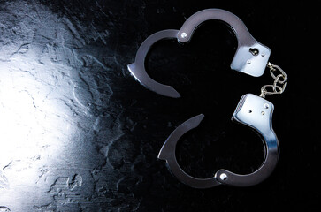 Police metal real handcuffs on the black background. Crime and robbery, prison concept.