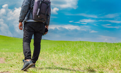 Adventurous man in the field, man with backpack in the field looking sideways, close up of steps of a young backpacker