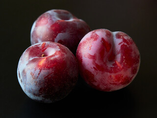 Ripe red plums on a dark background