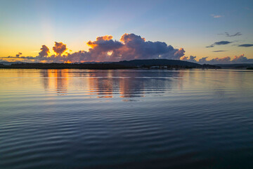Naklejka premium Aerial sunrise over the bay with clouds and reflections