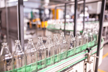 Glass factory, industrial production of glass containers. Modern technology, robots machines make products.Party bottles for drinks. Technological work at the plant. Working atmosphere with copy space