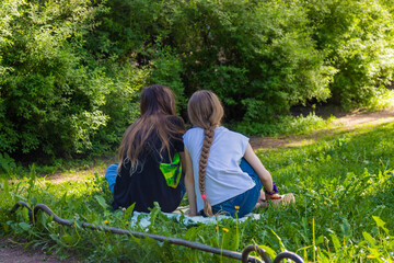 two girls are sitting on the grass in the park