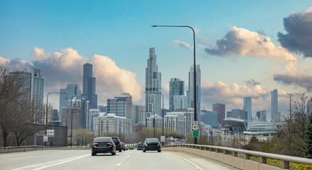 Chicago Illinois, USA. Cars on the road driving to Chicago city, high rise buildings and cloudy sky...
