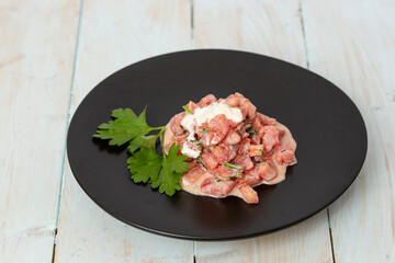 chopped tomatoes with sour cream and parsley on a black ceramic plate, side view