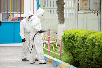 People in protective suits disinfect on the streets of the city. Epidemic corona virus, pandemic...