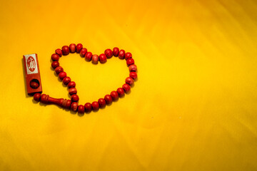 A prayer beads shaped a heart on yellow background