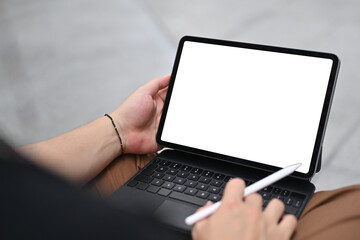 Cropped image of man hand using a white blank screen digital tablet and stylus pen that putting on his lap.