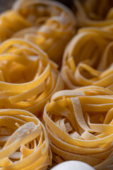 Homemade fettuccine pasta folded in the shape of a nest. Home cooking with ingredients for homemade...
