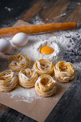 Homemade fettuccine pasta folded in the shape of a nest. Home cooking with ingredients for homemade traditional Italian fettuccine pasta.