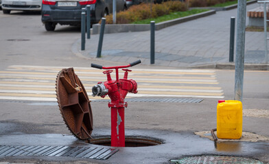 A red hydrant sticks out of the manhole