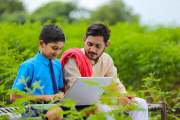 Education concept :cute indian school boy using laptop and giving some information to his father.