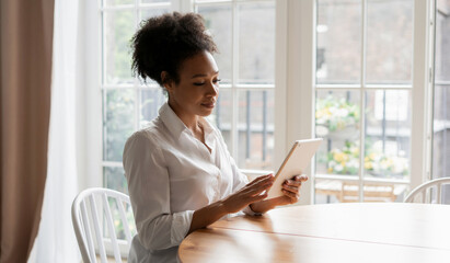 Work at home online on a tablet. A student surf the internet in search of information. The woman smiles and writes a message to the client by mail.  The hostess keeps records on the Internet.