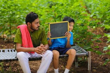 Fototapeta premium education concept : young indian farmer showing blank chalkboard with his child