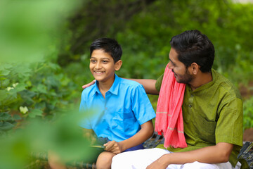 Cute indian farmer child in school uniform with his father at agriculture field