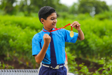 Clever schoolboy showing medal as a winner in school competition.