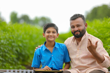 Cute indian farmer child studying with his father at home