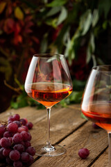 Autumn cozy romantic evening outdoors, wooden table with glasses with rose wine and grapes