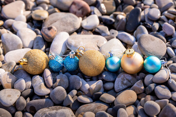 New year at the beach. Christmas ornaments standing on stones near the water.Christmas holiday decorations, balls on a beach at a tropical island during vacation