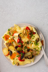 Fettuccine pasta with stewed vegetables, delicious autumn lunch in plate with mustard and fresh green onions