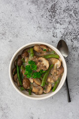 Fried brown champignons mushrooms with green beans in a creamy sauce with green onions and parsley, top view