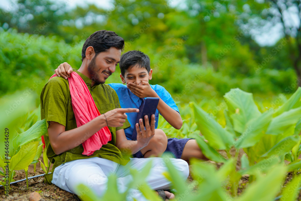 Canvas Prints Indian farmer using smartphone with his child at green turmeric agriculture field.