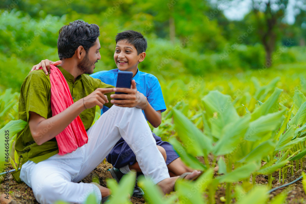 Canvas Prints Indian farmer using smartphone with his child at green turmeric agriculture field.