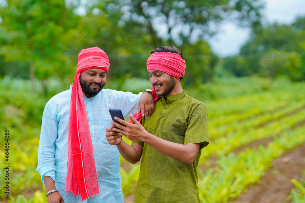 Poster Indian farmer using smartphone at green turmeric agriculture field.