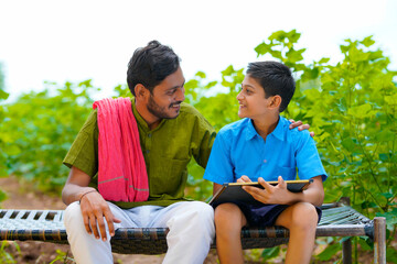 Cute indian farmer child studying with his father at home