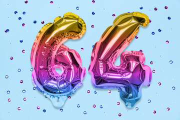 Rainbow foil balloon number, digit sixty four on a blue background with sequins. Birthday greeting card with inscription 64. Top view. Numerical digit. Celebration event, template.