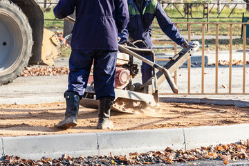 worker compresses sand for paving slabs with special working tool - tamping machine or vibratory...